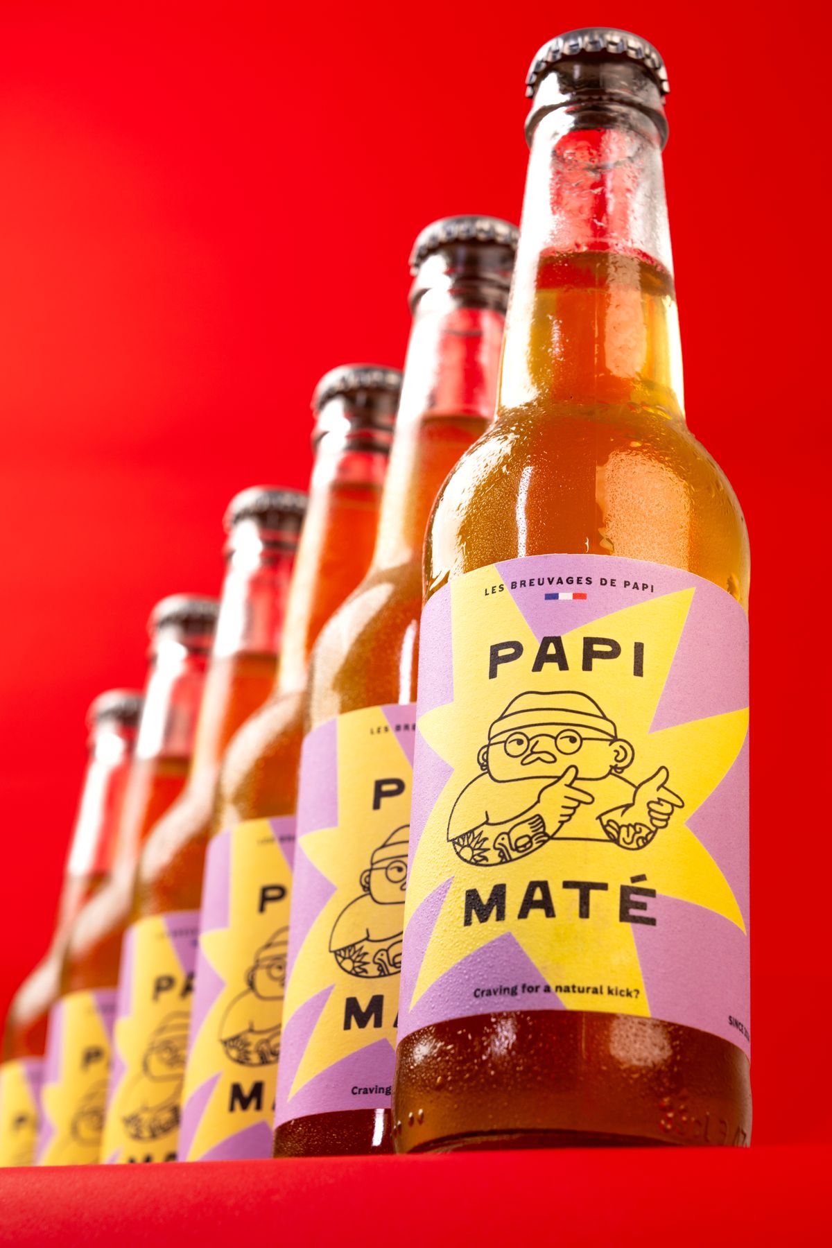 Bouteilles Papi Maté alignées sur fond rouge
