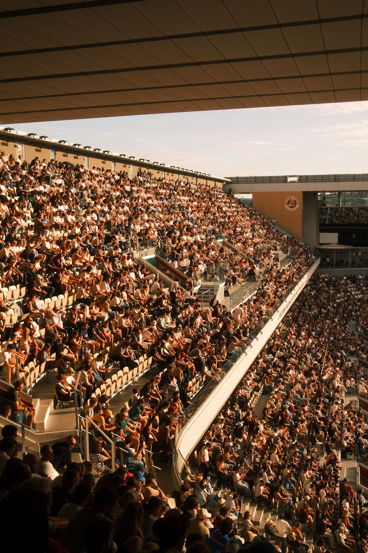 Tribunes pleines d'un court de tennis en fin de journée
