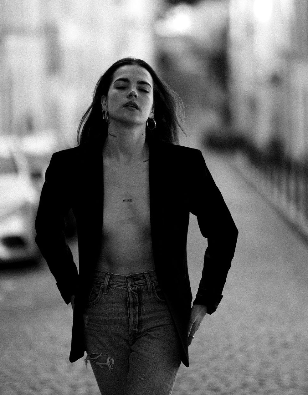 Femme en veste noire dans une rue pavée, noir et blanc