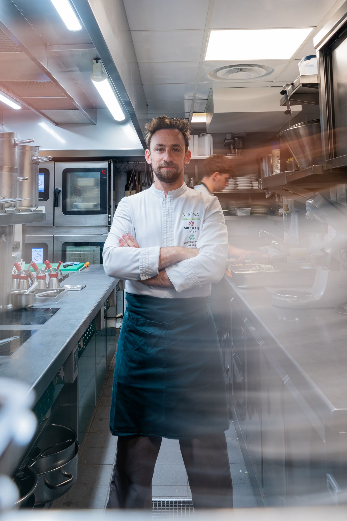 Chef en tablier dans sa cuisine, bras croisés